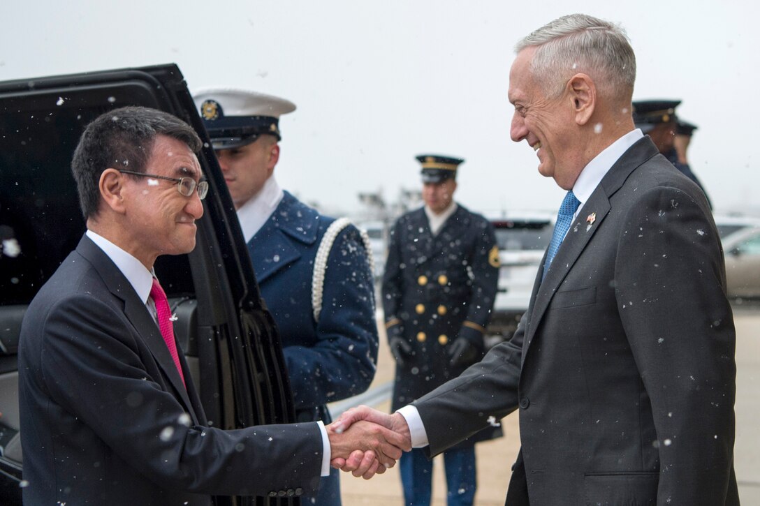 Defense Secretary James N. Mattis shakes hands with a person near a vehicle.