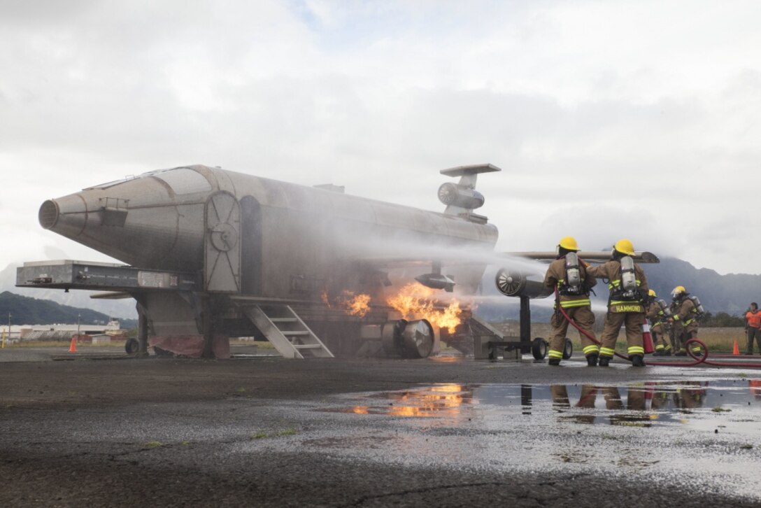 U.S. Marines with Aircraft Rescue Fire Fighting (ARFF) extinguish a fire from a training aircraft during a wheel fire exercise at West Field, Marine Corps Air Station, Feb. 2, 2018. ARFF conducted a wheel fire exercise to improve proficiency in assessing and extinguishing a fire by utilizing the Mobile Aircraft Firefighting Training Device. (U.S. Marine Corps photo by Cpl. Jesus Sepulveda Torres)