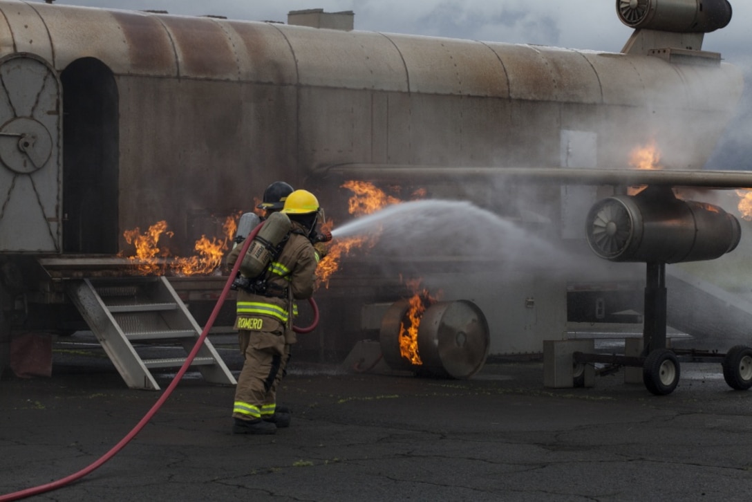 U.S. Marines with Aircraft Rescue Fire Fighting (ARFF) extinguish a fire from a training aircraft during a wheel fire exercise at West Field, Marine Corps Air Station, Feb. 2, 2018. ARFF conducted a wheel fire exercise to improve proficiency in assessing and extinguishing a fire by utilizing the Mobile Aircraft Firefighting Training Device. (U.S. Marine Corps photo by Cpl. Jesus Sepulveda Torres)