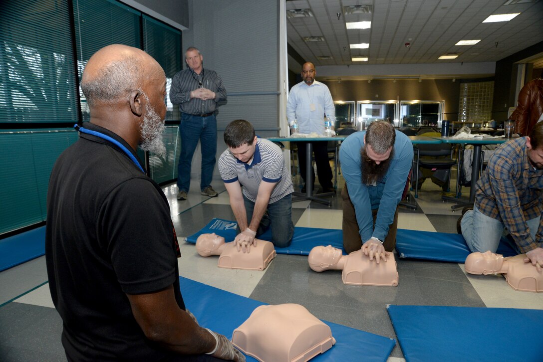 Red Cross instructor Victor Churchill watches as employees of the U.S. Army Engineering and Support Center, Huntsville, practice chest compressions on medical dummies during a first aid and CPR training and certification session March 1 at the Center. Along with their primary duties, the employees serve as first aid attendants for Huntsville Center and must certify annually.