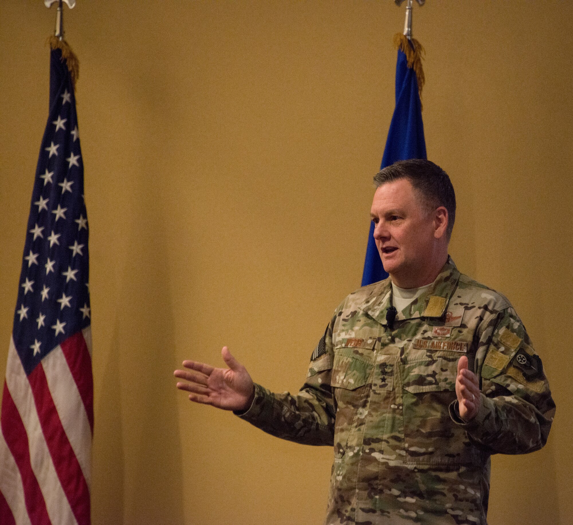 One person speaking with flags in the background.
