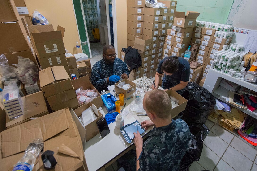 Sailors organize medical prescriptions at a table.