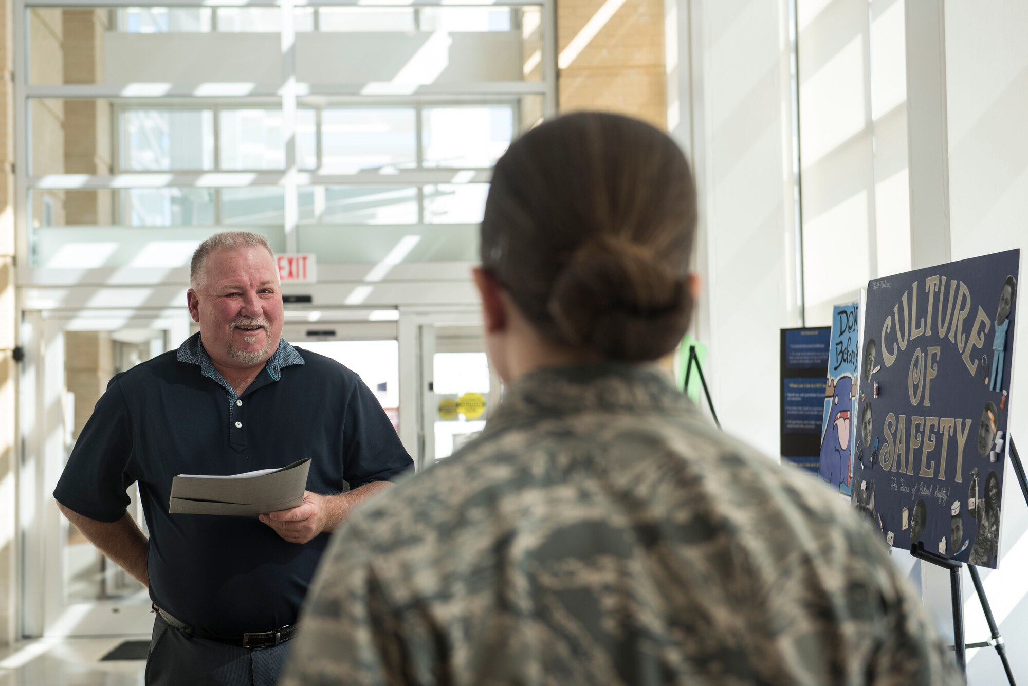 Jeff White, 20th Medical Group patient safety program manager, asks U.S. Air Force Airman 1st Class Tessa Tugo, 20th Medical Support Squadron laboratory technician, about her poster during a contest at Shaw Air Force Base, S.C., March 15, 2018.