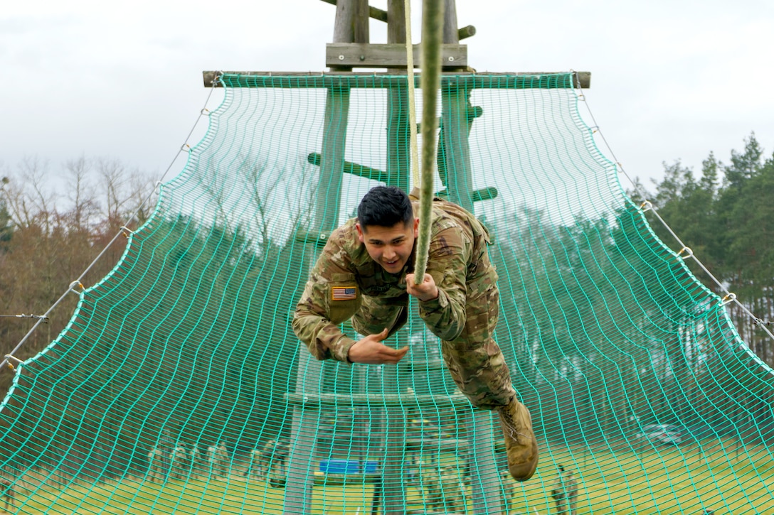 A soldier moves down a rope above a green net.