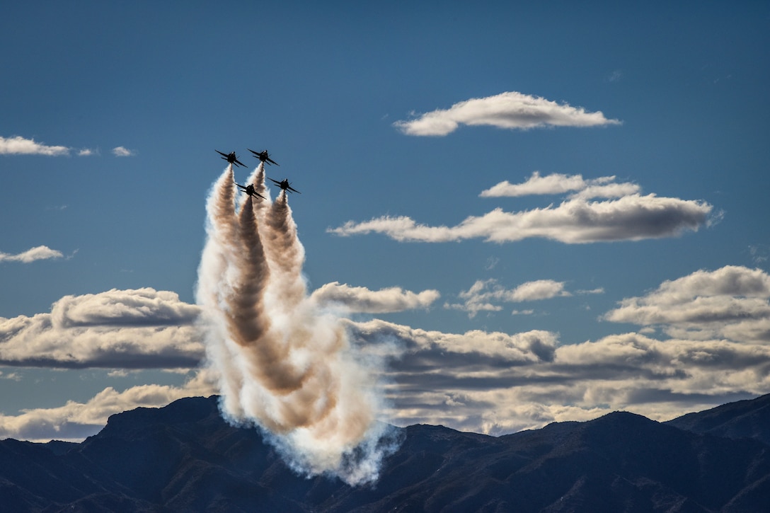 Navy pilots flying four aircraft fly vertically at an air show.