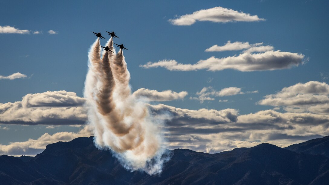 Navy pilots flying four aircraft fly vertically at an air show.