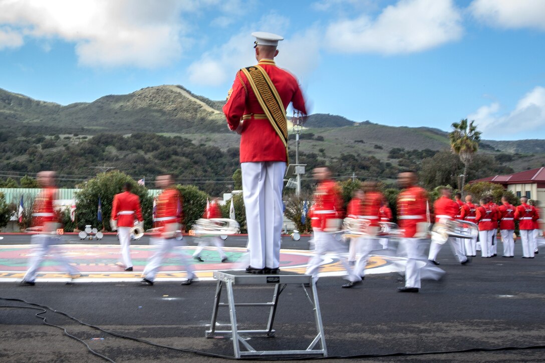 Marines wearing red move in front of mountains.