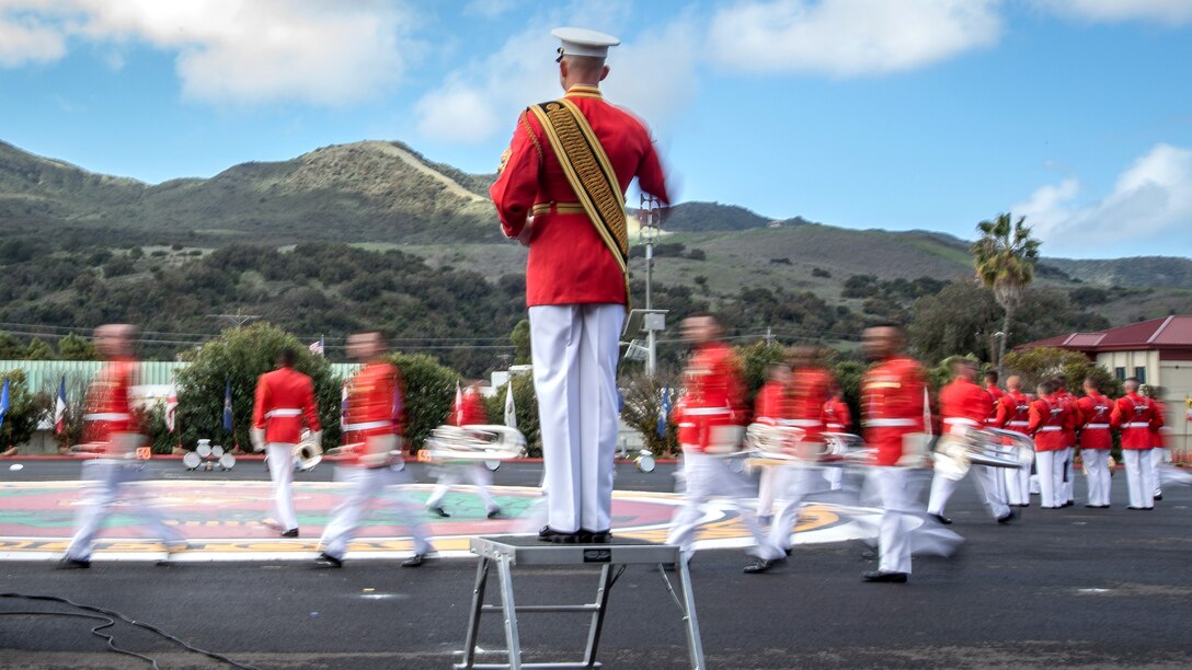 Marines wearing red move in front of mountains.