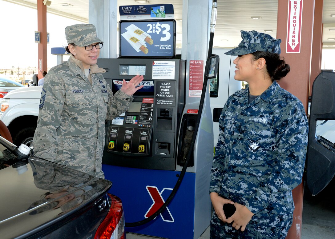 Navy Airman Laniesha Berg, VX-9 Detachment 1 (right) gets a surprise from Master Sgt. Brittany Ponder, 31st Test and Evaluation Squadron first sergeant, at the Express gas station March 14. The Edwards First Sergeants Council conducted a "random-act-of-kindness" event where they paid for and offered to pump gas for junior servicemembers and spouses. (U.S. Air Force photo by Kenji Thuloweit)
