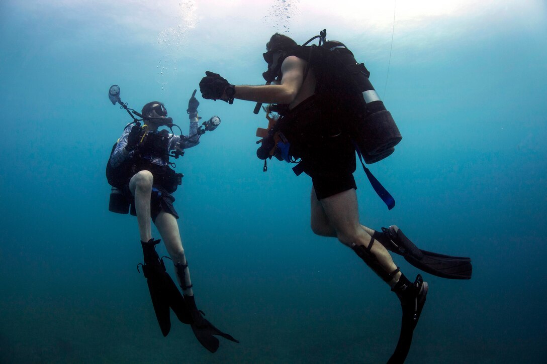 A diver signals another diver as they ascend at the end of a dive.