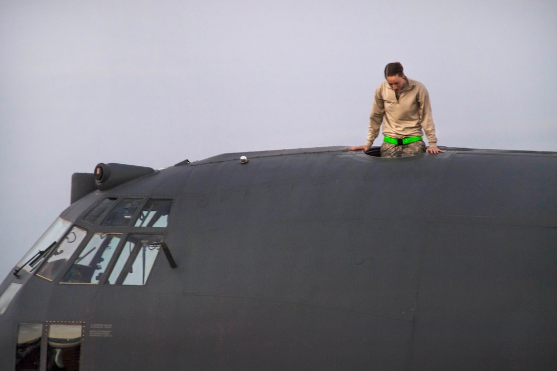 An airman exits the top of the MC-130H Combat Talon aircraft.