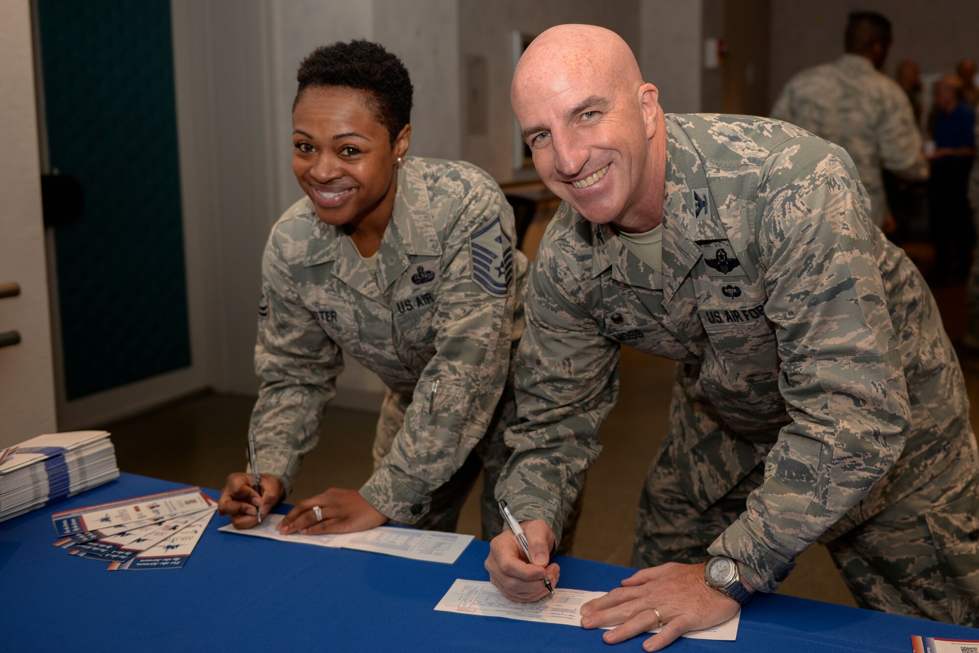 Col. Kenneth Moss, 374th Airlift Wing commander, right, and Master Sgt. Dierdre Mister, 374th Medical Group first sergeant, left, fill out pledge forms for the Air Force Assistance Fund at Yokota Air Base, Japan, Mar. 20, 2018.