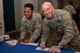 Col. Kenneth Moss, 374th Airlift Wing commander, right, and Master Sgt. Dierdre Mister, 374th Medical Group first sergeant, left, fill out pledge forms for the Air Force Assistance Fund at Yokota Air Base, Japan, Mar. 20, 2018.