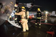 Firefighters from the 379th Expeditionary Civil Engineer Squadron and Qatar Emiri Air Force collaborate in a joint training exercise at Al Udeid Air Base, Qatar, Feb. 28, 2018. The exercise, a simulated response to a C-130 Hercules aircraft fire emergency, marks the first instance of the partner forces responding together in the same vehicles. (U.S. Air Force photo by Staff Sgt. Joshua Horton)