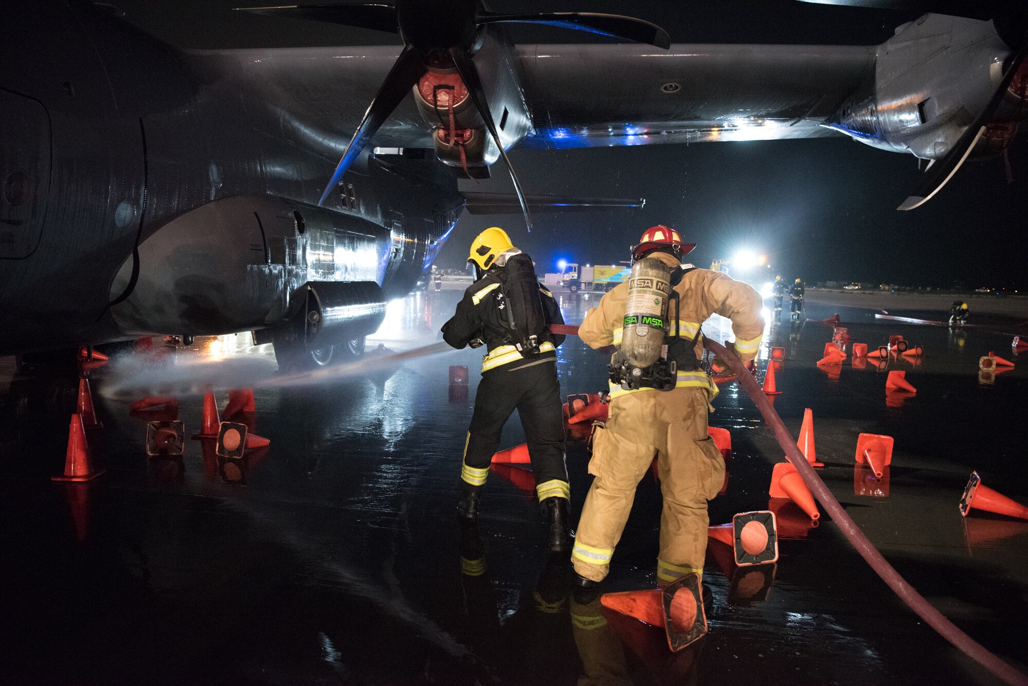 Firefighters from the 379th Expeditionary Civil Engineer Squadron and Qatar Emiri Air Force collaborate in a joint training exercise at Al Udeid Air Base, Qatar, Feb. 28, 2018. The exercise, a simulated response to a C-130 Hercules aircraft fire emergency, marks the first instance of the partner forces responding together in the same vehicles. (U.S. Air Force photo by Staff Sgt. Joshua Horton)