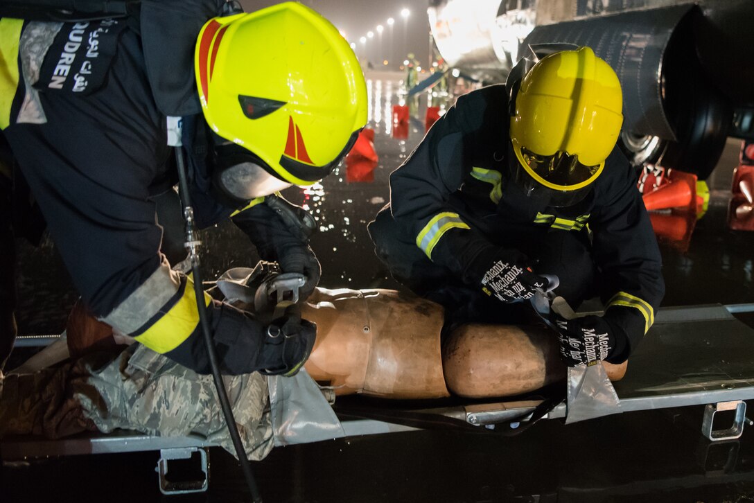 Firefighters from the 379th Expeditionary Civil Engineer Squadron and Qatar Emiri Air Force collaborate in a joint training exercise at Al Udeid Air Base, Qatar, Feb. 28, 2018. The exercise, a simulated response to a C-130 Hercules aircraft fire emergency, marks the first instance of the partner forces responding together in the same vehicles. (U.S. Air Force photo by Staff Sgt. Joshua Horton)