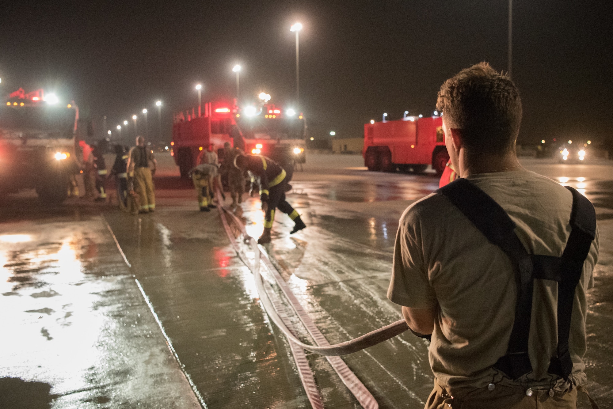 Firefighters from the 379th Expeditionary Civil Engineer Squadron and Qatar Emiri Air Force collaborate in a joint training exercise at Al Udeid Air Base, Qatar, Feb. 28, 2018. The exercise, a simulated response to a C-130 Hercules aircraft fire emergency, marks the first instance of the partner forces responding together in the same vehicles. (U.S. Air Force photo by Staff Sgt. Joshua Horton)
