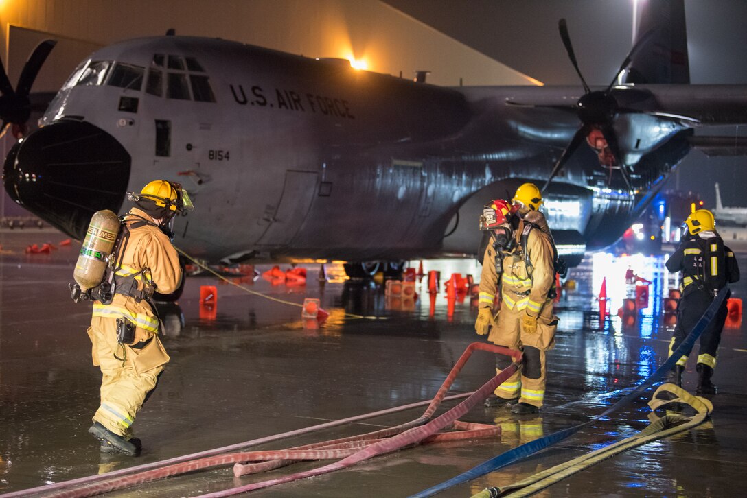 Firefighters from the 379th Expeditionary Civil Engineer Squadron and Qatar Emiri Air Force collaborate in a joint training exercise at Al Udeid Air Base, Qatar, Feb. 28, 2018. The exercise, a simulated response to a C-130 Hercules aircraft fire emergency, marks the first instance of the partner forces responding together in the same vehicles. (U.S. Air Force photo by Staff Sgt. Joshua Horton)