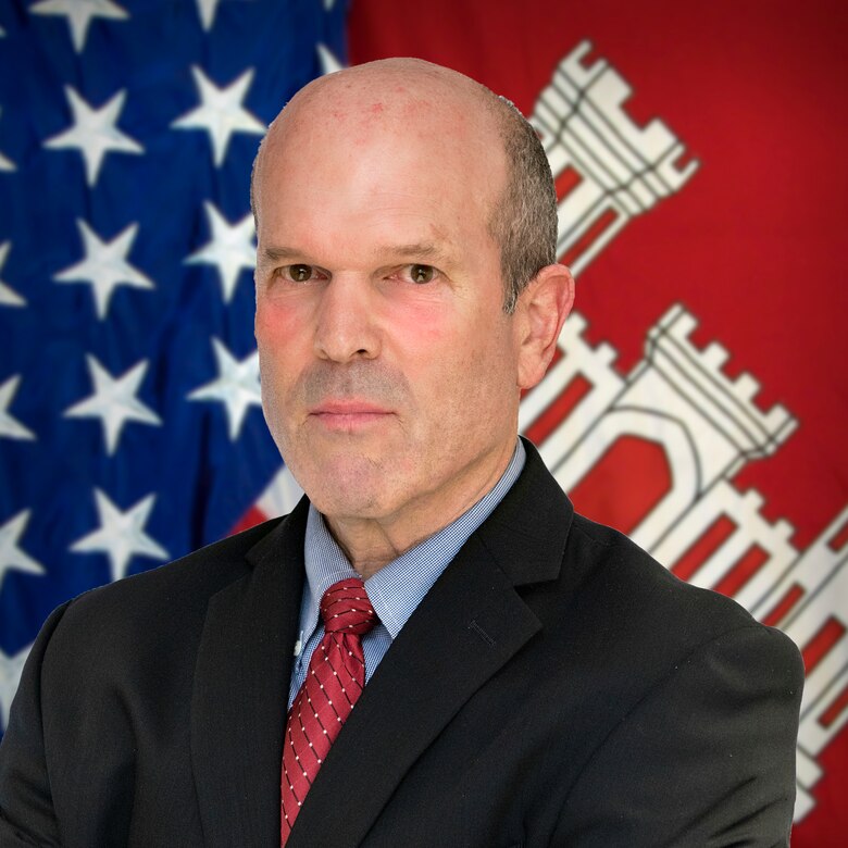 A man poses in front of the American and USACE flags.
