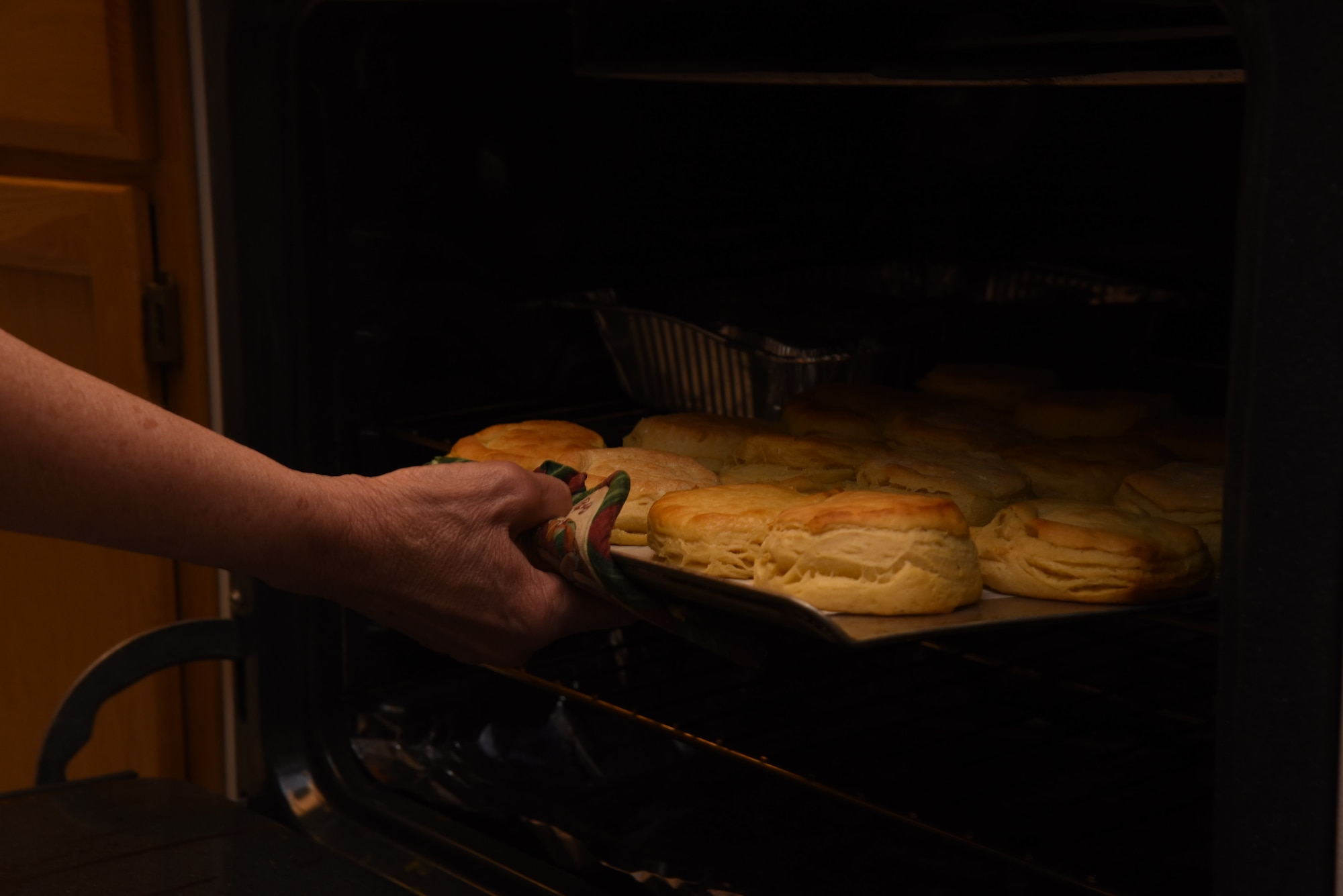 Just before dinner is ready, Airmen volunteers help out the Higher Grounds directors with last-minute tasks such as baking biscuits at F.E. Warren Air Force Base, Wyoming, March 14, 2018. Higher Grounds provides Airmen with volunteer opportunities within the facility and in the community. (U.S. Air Force photos by Airman 1st Class Abbigayle Wagner)