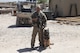 U.S. Air Force Staff Sgt. David Mussio, 20th Security Forces Squadron (SFS) military working dog (MWD) trainer, stands with MWD Marky in a deployed location, circa 2015.