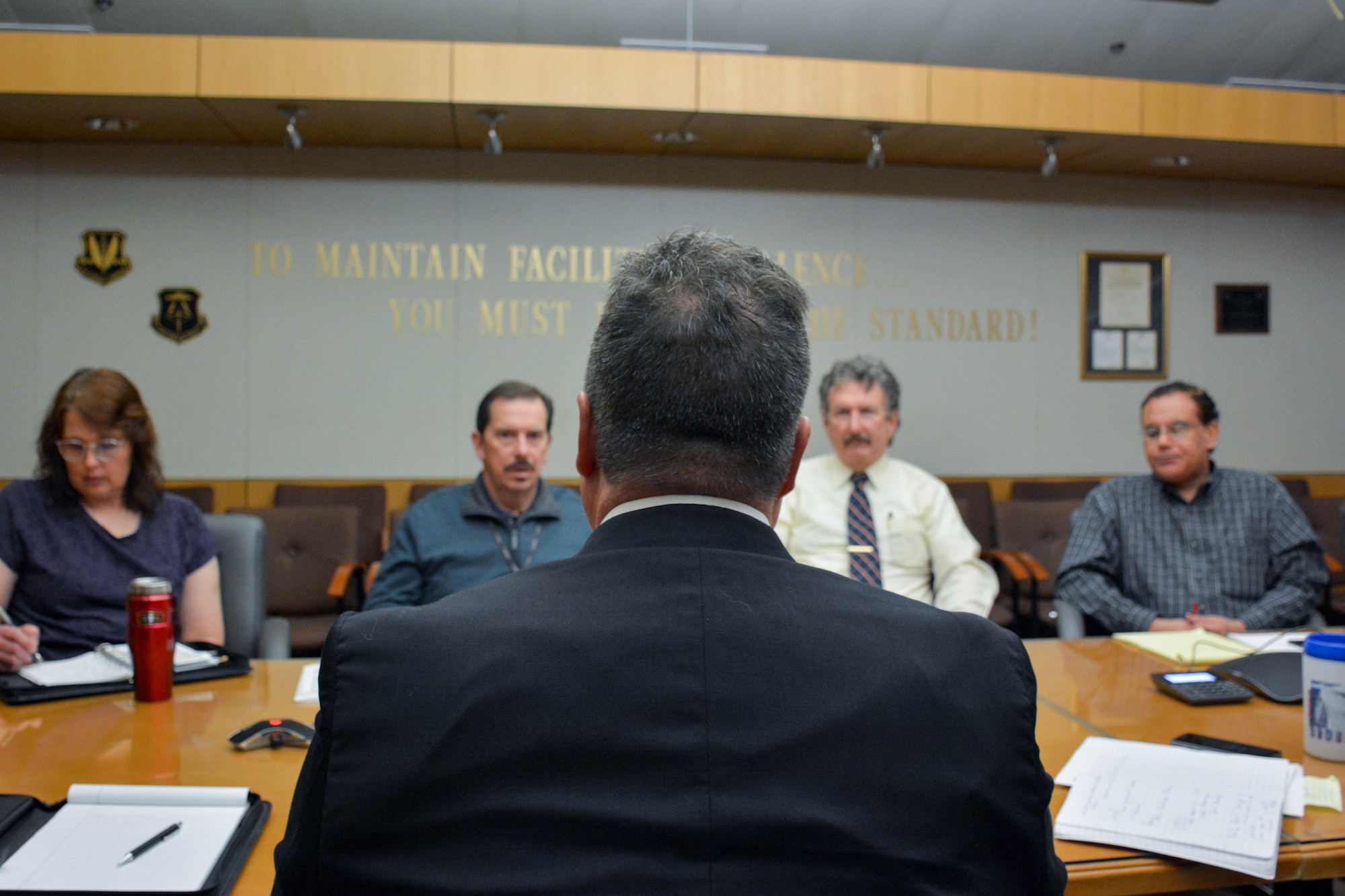 Man in center, looks across table towards four others