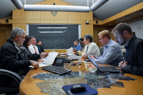 low-angle photo of nine people surrounding a table