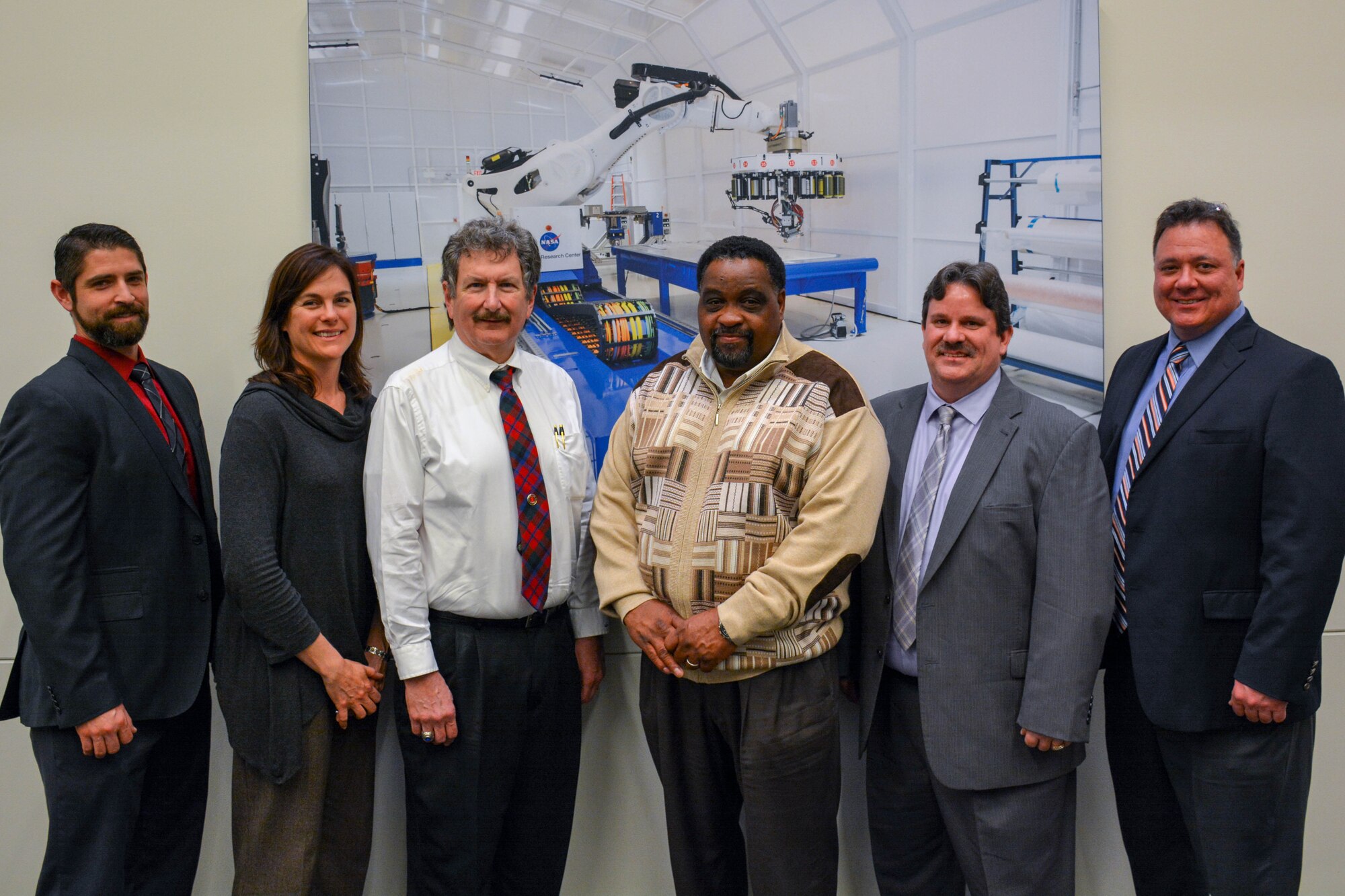 Six individuals pose in front of photo at NASA Langley Research Center