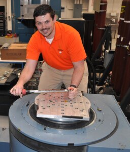 IMAGE: DAHLGREN, Va. - Naval Surface Warfare Center Dahlgren Division (NSWCDD) engineer Shawn Schneider mounts an adapter plate to an Unholtz-Dickie T-2000 electro-dynamic vibration system capable of providing over 24,000 pounds of force in vibration at frequencies up to and exceeding 3,000 hertz (cycles per second). These systems are used to replicate shock and vibration environments experienced by test items during their lifecycle to ensure that performance and safety are not compromised prior to use by the warfighter. NSWCDD announced on March 20 that Schneider won the 2018 Department of the Navy Award for Technical Excellence at a Test and Evaluation Facility or Range. The engineer was honored for extraordinary scientific and engineering contributions to the test and evaluation community in the area of multi-input-multi-output vibration test profiles.