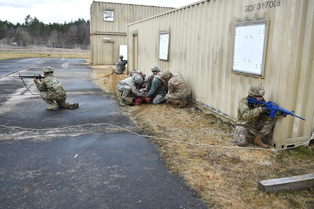 Soldiers provide security while team members prepare to evacuate a simulated casualty.