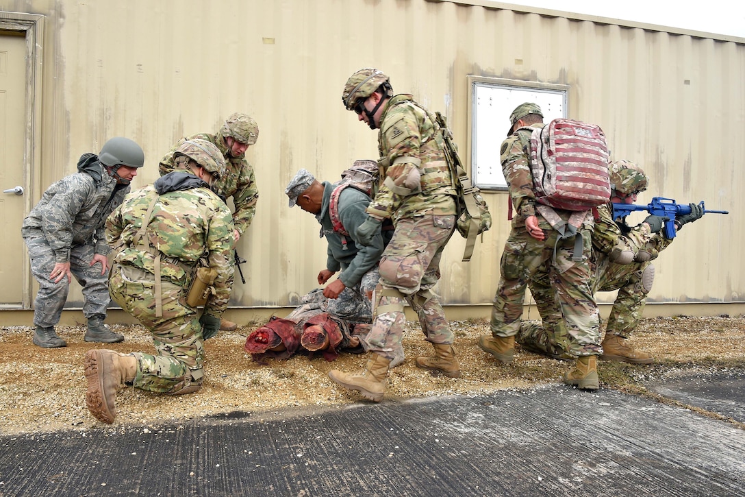 Soldiers provide medical aid before evacuating a simulated casualty.