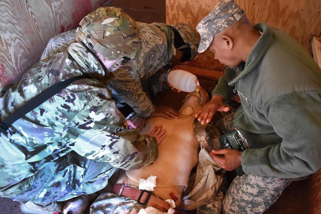 Soldiers apply medical aid to clear the airway on a simulated casualty.