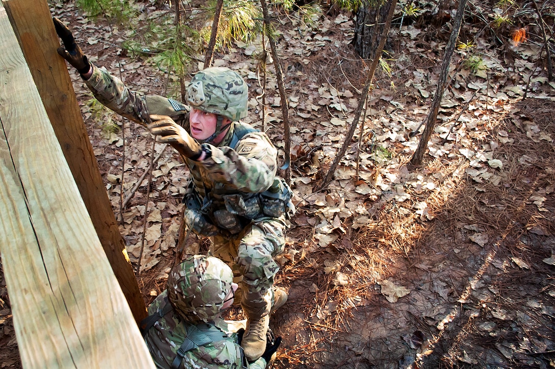 Soldiers negotiate wall obstacle.