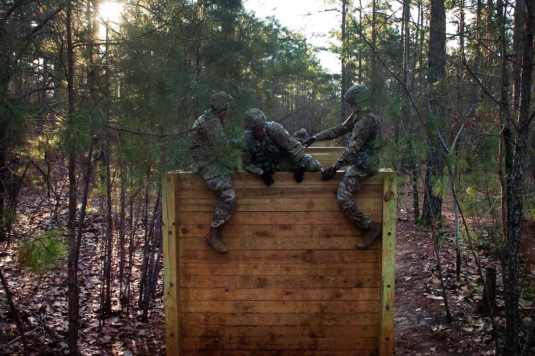 Soldiers work as a team to negotiate high wall obstacles.