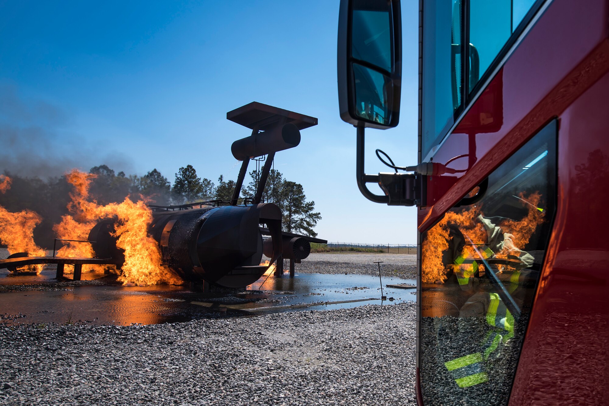 Fire from an aircraft simulator reflects onto the window of an aircraft rescue firefighting vehicle during a live-fire burn exercise, March 16, 2018, at Moody Air Force Base, Ga.Firefighters from the 23d CES conducted the exercise to demonstrate their firefighting capabilities to community leaders and Moody’s honorary commanders. (U.S. Air Force photo by Airman Eugene Oliver)