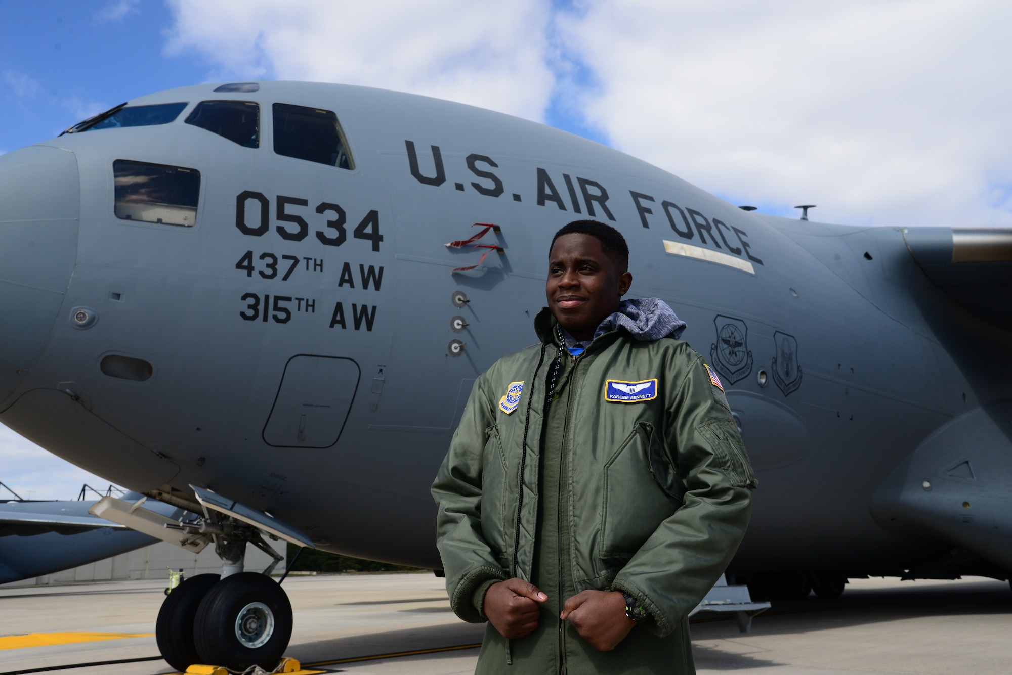 Kareem Bennett, 3rd Airlift Squadron honorary pilot for a day, stands in front of a C-17 Globemaster III March 16, 2018, on the flightline at Dover Air Force Base, Del. Bennett, a patient at Alfred I. duPont Hospital for Children in Wilmington, Del., was invited by the squadron to spend the day with them and learn what the Air Force is all about. (U.S. Air Force photo by Staff Sgt. Aaron J. Jenne)
