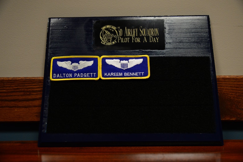 Two nametapes cling to the 3rd Airlift Squadron Pilot for a Day plaque March 16, 2018, at Dover Air Force Base, Del. Dalton Padgett and Kareem Bennett are both remembered as life-long honorary members of the squadron after their participation in the Pilot for a Day program. (U.S. Air Force photo by Staff Sgt. Aaron J. Jenne)