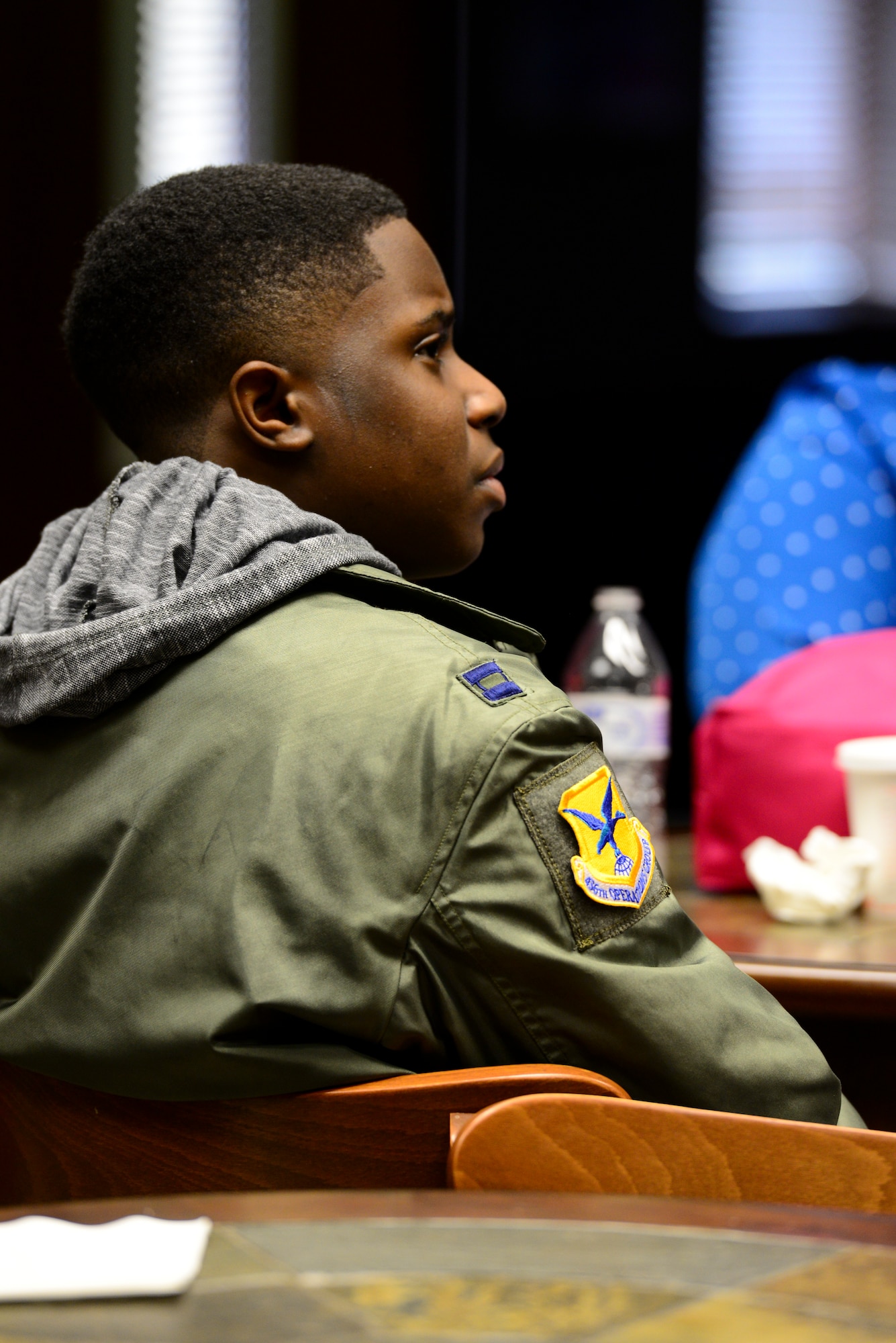 Kareem Bennett listens to a conversation March 16, 2018, in the 3rd Airlift Squadron heritage room on Dover Air Force Base, Del. Bennett was invited to spend a day with members of the 3rd AS and became an honorary pilot for the day. (U.S. Air Force photo by Staff Sgt. Aaron J. Jenne)