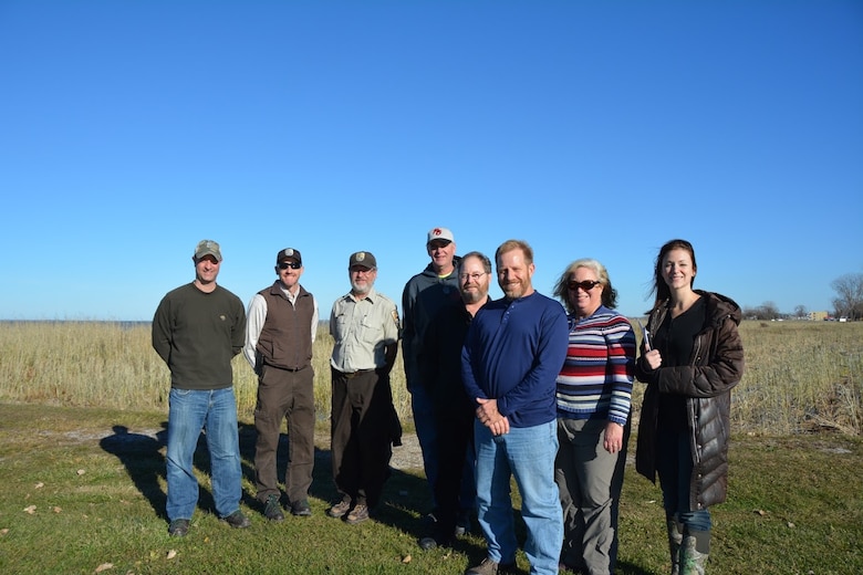 Pictured are Chris Akios (USACE), Jason Lewis (US Fish and Wildlife Service), Ron Huffman (USFWS), Tracy Colston (City of Port Clinton), Mayor Hugh Wheeler (City of Port Clinton), Mike Kelly (Ohio Environmental Protection Agency), Linda Merchant-Masonbrink (OEPA), and Angela Adkins (OEPA).  

In the background, the Port Clinton site featuring the dominance of Phragmites. While picturesque, this plant monoculture does not support a diversity of plants and animals. The current project aims to change that and restore the site to support a variety of native plants and animals.(Picture by Gerlyn Hinds, USACE)