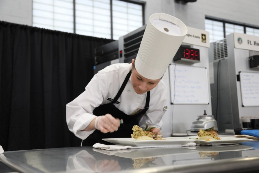 An Army chef plates a chicken dish.