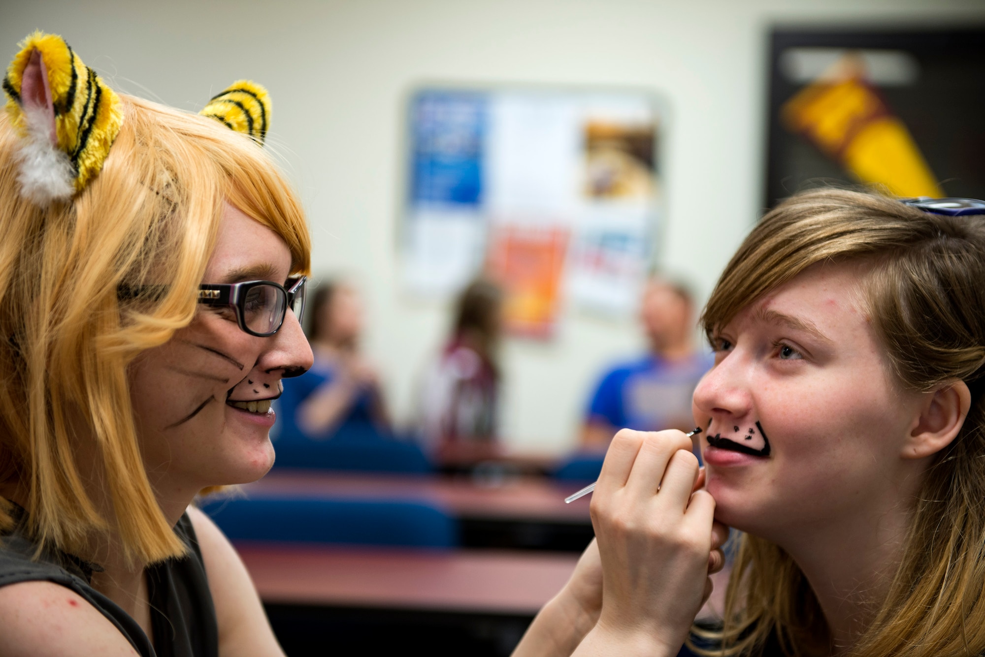 Rebecca Straton, left, convention programming director, paints the face of Madison, convention guest, while at a face painting seminar during Cub Con, a multi-genre entertainment convention, March 17, 2018, at Moody Air Force Base, Ga. The convention was held to spread awareness of the library’s new weekend hours as well as get people excited for Tiger Con, scheduled for April 14-15. (U.S. Air Force photo by Airman 1st Class Erick Requadt)