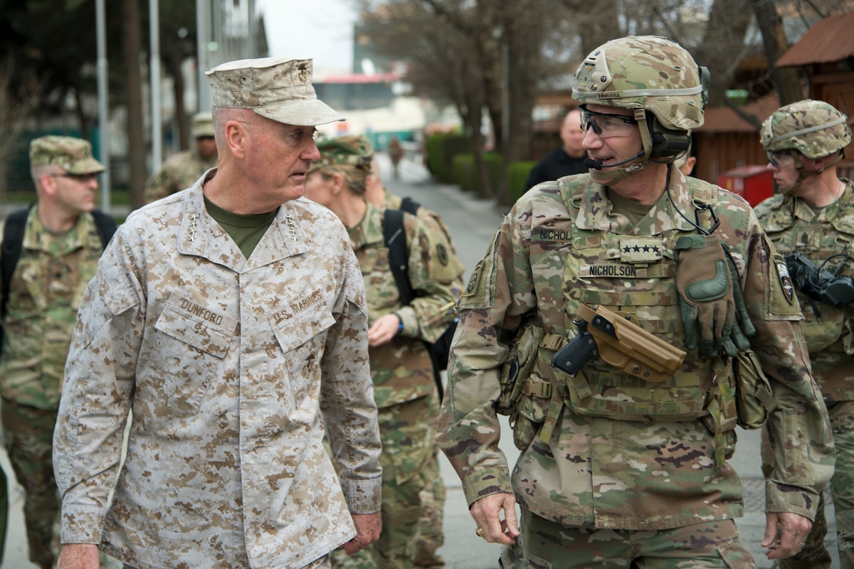 Two U.S. military leaders converse as they walk down a street in Afghanistan.