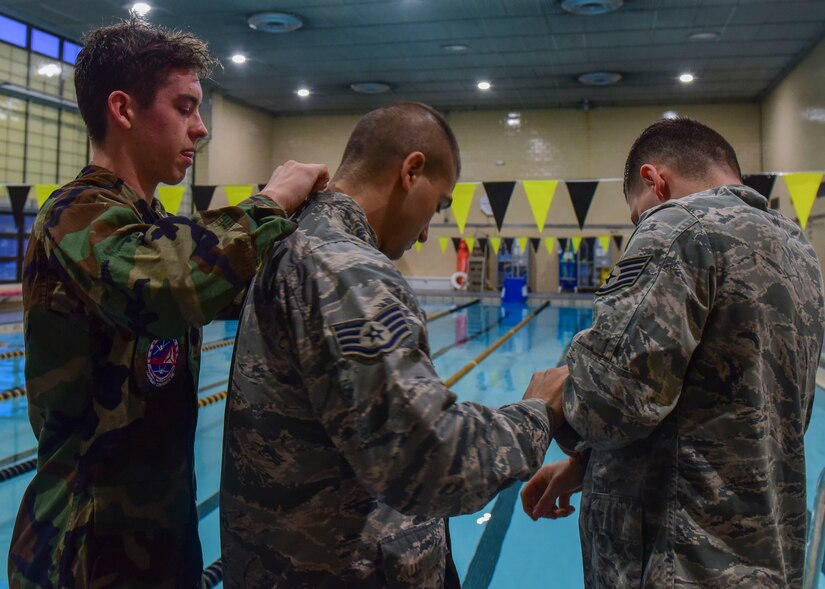 (From Left) U.S. Civil Air Patrol Cadet 1st Lt. Thomas Hall, U.S. Air Force Staff Sgt. Michael Svoleantopoulos, 497th Operation Support Squadron weapons tactician, and U.S. Air Force Staff Sgt. Dajon Begin, 45th Intelligence Squadron full motion video imagery mission supervisor, help each other prepare their uniforms for the pool at Fort Eustis’ Anderson Field House at Joint Base Langley-Eustis, Virginia, March 6, 2018.