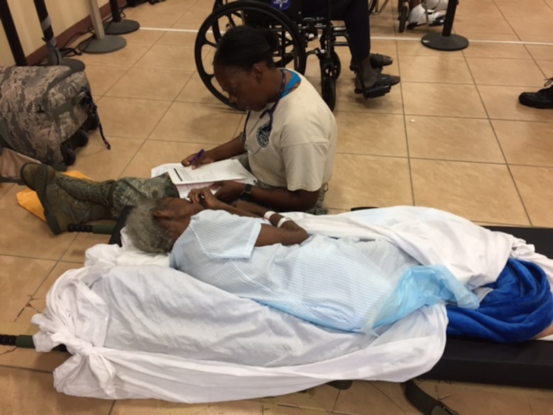 Maj. Kisha Wood, a medic with the 375th Medical Group based at Scott Air Force Base, assists an elderly patient after Hurricane Maria at Henry E. Rohlsen Airport, near Christiansted, St. Croix, U.S. Virgin Islands Sept. 24, 2017. Wood was part of a U.S. Air Force En Route Patient Staging System team that deployed to St. Croix to help evacuate patients off the island. The team created an aeromedical evacuation staging area for patients to evacuate, fostering a safe environment. (Photo by Lt. Col. Elizabeth Anderson-Doze)
