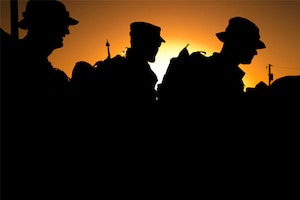 A silhouette of three service members.