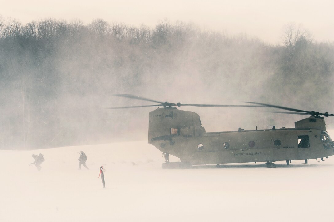 Soldiers disembark from a helicopter and move out to their objective.