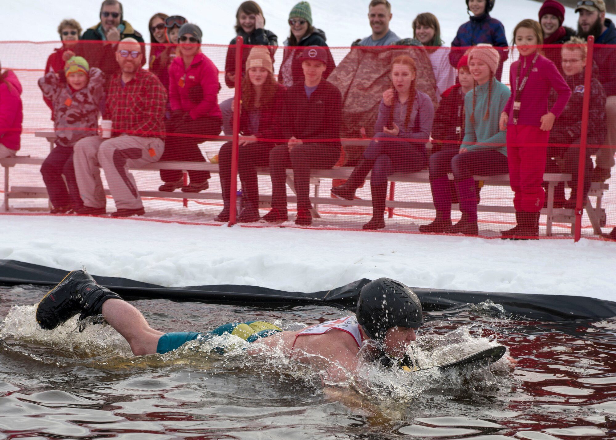 Ross Funches, a participant of the 2018 Slush Cup, swims to the finish line at Joint Base Elmendorf-Richardson’s Hillberg Ski Area, March 18, 2018.The Slush Cup is a two-fold annual event celebrating the change in weather, consisting of skiers and snowboarders trying to make it across a man-made slush pond without falling.