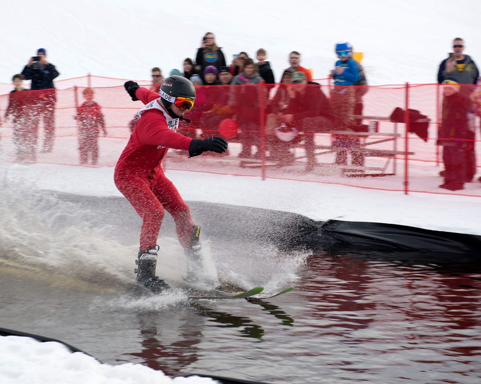 Ben Fenaughty, a participant of the 2018 Slush Cup, skids across the pond to the finish line at Joint Base Elmendorf-Richardson’s Hillberg Ski Area, March 18, 2018. The Slush Cup is a two-fold annual event celebrating the change in weather, consisting of skiers and snowboarders trying to make it across a man-made slush pond without falling.