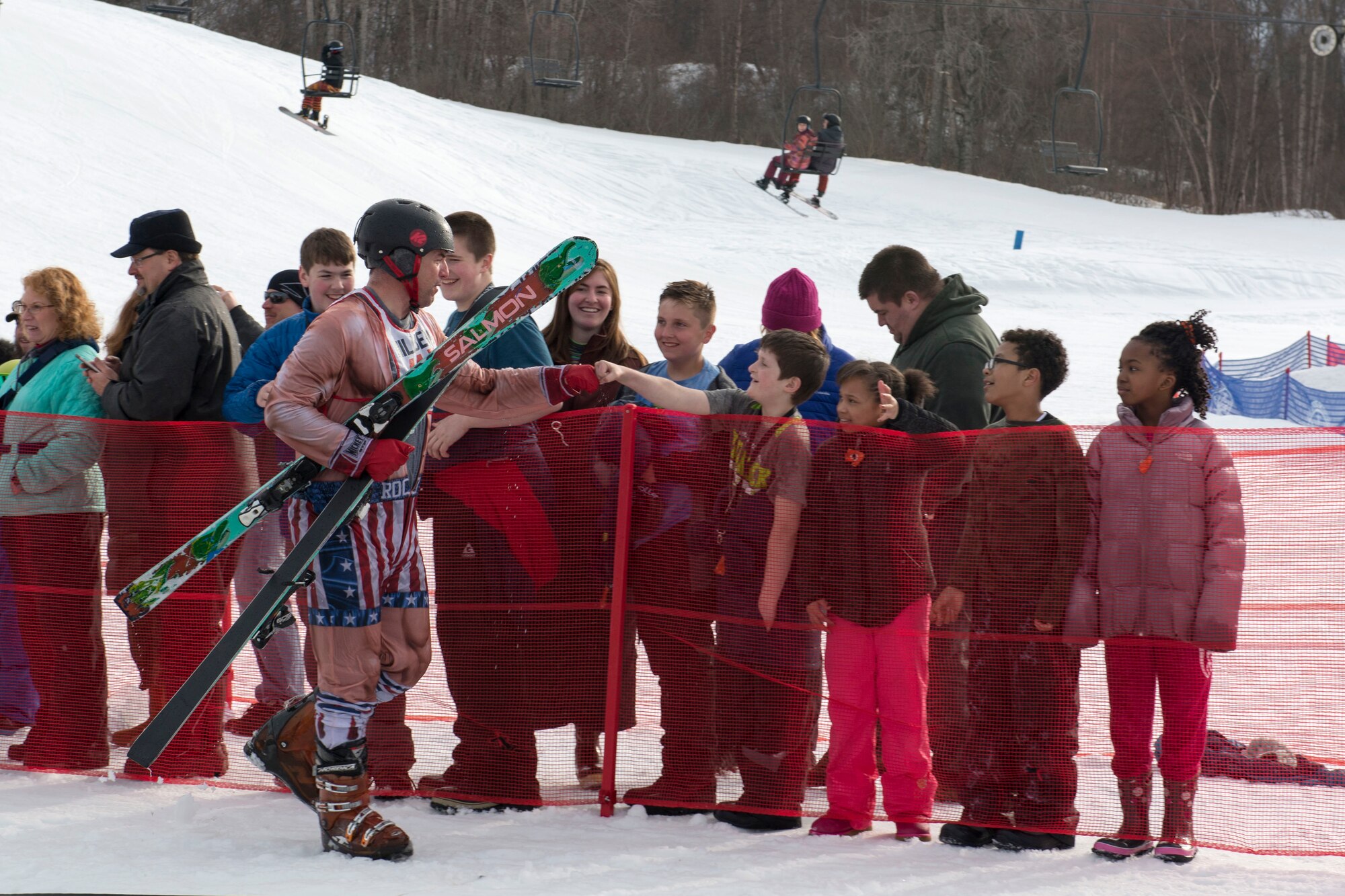 John Androski, a participant of the 2018 Slush Cup, interacts with the crowd after completing his jump at Joint Base Elmendorf-Richardson’s Hillberg Ski Area, March 18, 2018. The Slush Cup is a two-fold annual event celebrating the change in weather, consisting of skiers and snowboarders trying to make it across a man-made slush pond without falling.