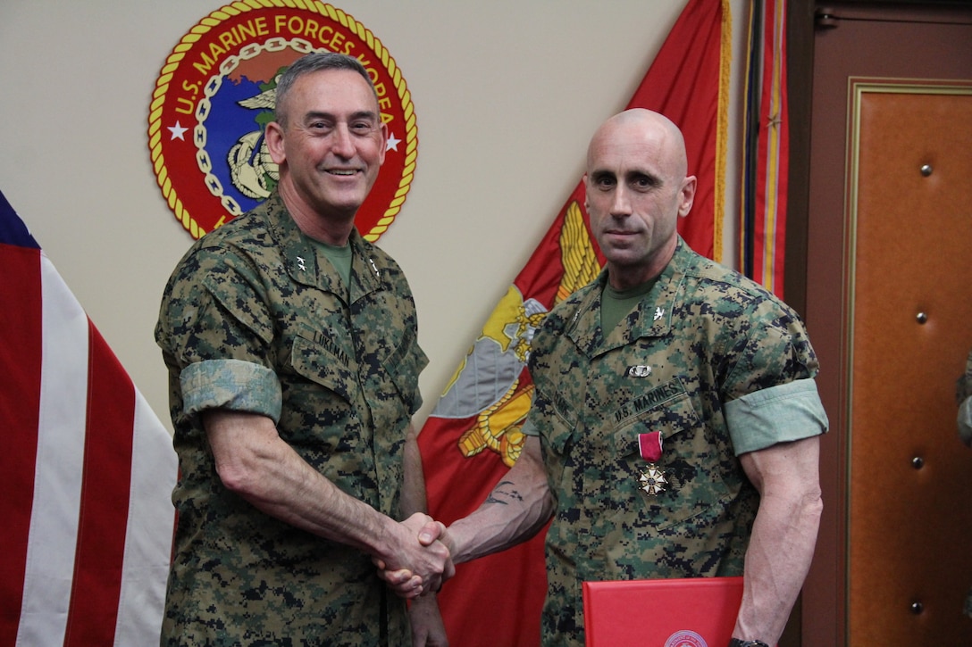 Maj. Gen. James W. Lukeman (left), assistant chief of staff of Plans and Policy for United Nations Command, Combined Forces Command, and U.S. Forces Korea, shakes hands with Col. William P. Clark, deputy commander of U.S. Marine Corps Forces Korea, after awarding him the Legion of Merit medal, March 15, 2018. (Official U.S. Marine Corps Photo by Sgt. Nathaniel Hanscom/Released)